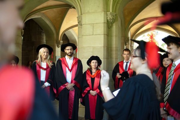 PhD graduates dressed in graduation gowns