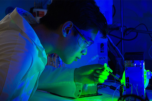 Scientist looking into instrument emitting blue and green light